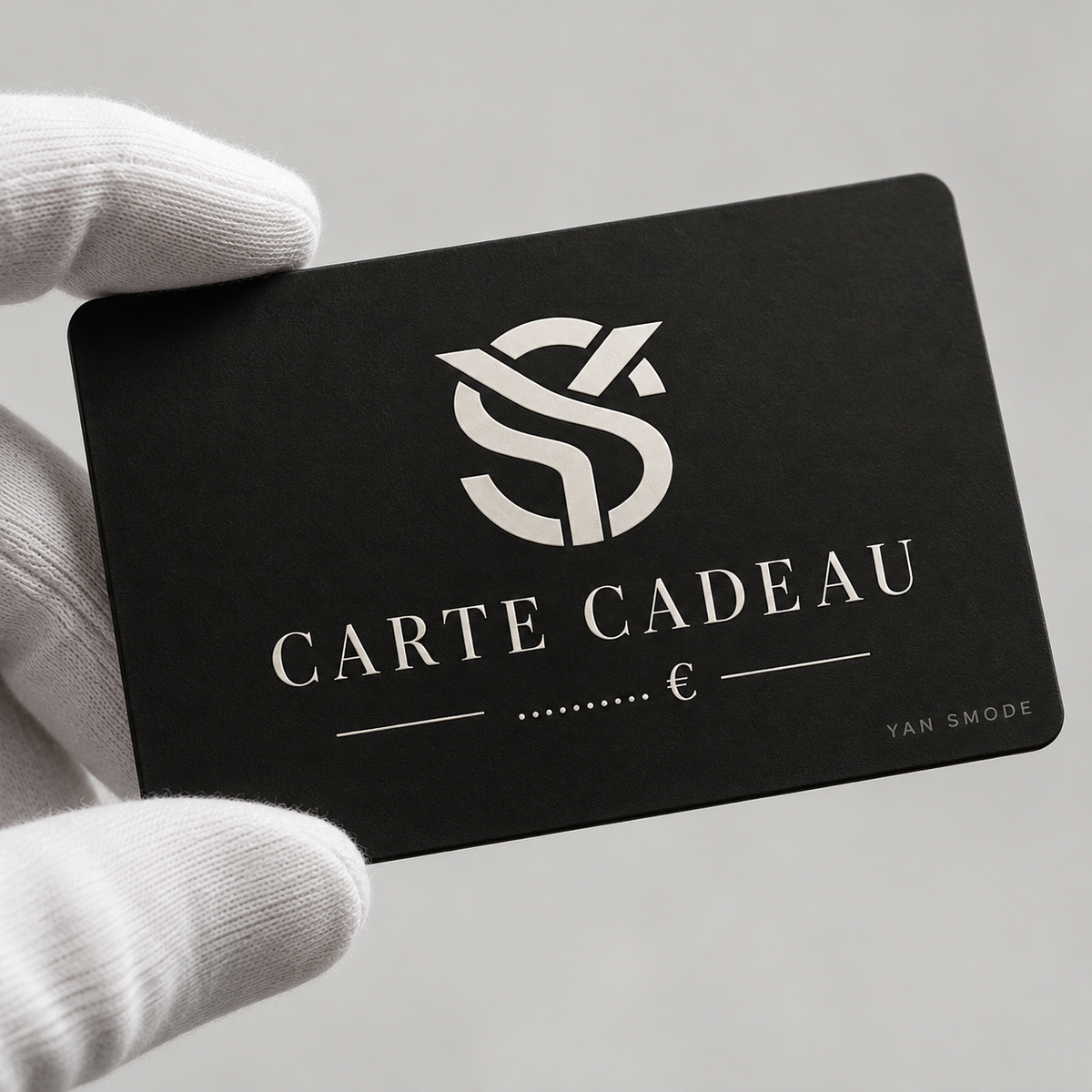Carte cadeau Yan Smode noire tenue par une main gantée de blanc